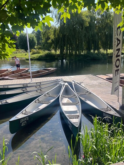 A row of canoes docked at a pier with a person standing in one. 2