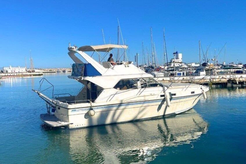 A white yacht docked at a marina with calm water and clear skies. 3
