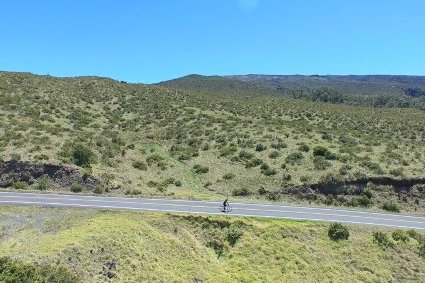 A cyclist on a road with a hilly landscape in the background. 5