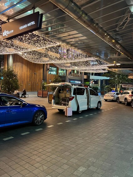 A Grand Hotel entrance with a white van and a blue car parked in front. 1