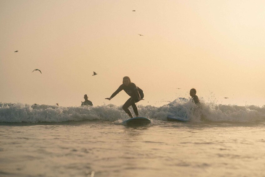 Surfers riding waves at sunset. 5