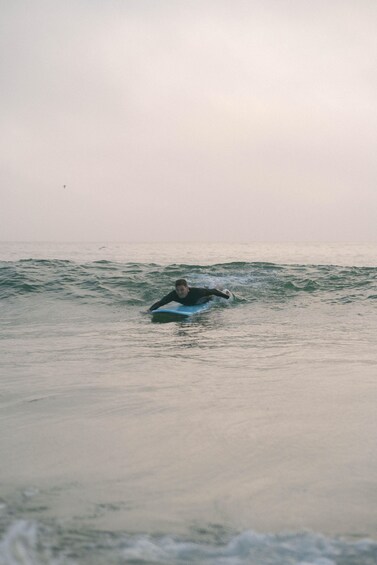 A person surfing on a blue board in the ocean. 4