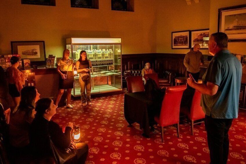 A bar with red chairs, a bar counter, and a display case with bottles. 2