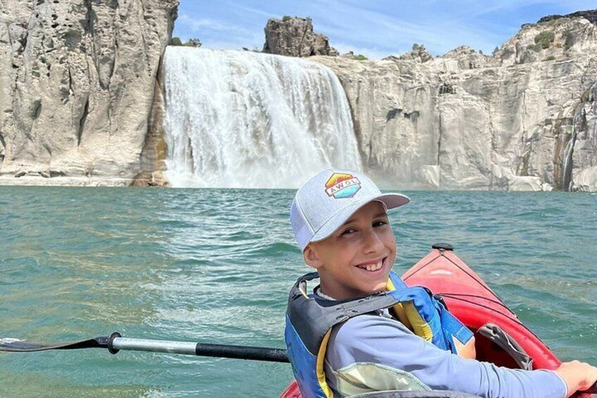 A person kayaking with a waterfall in the background. 5