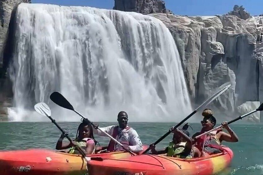 A group kayaking in front of a waterfall. 1