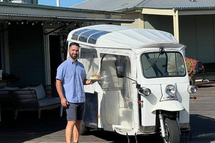 A vintage camper van parked in front of a house with a person standing beside it. 2