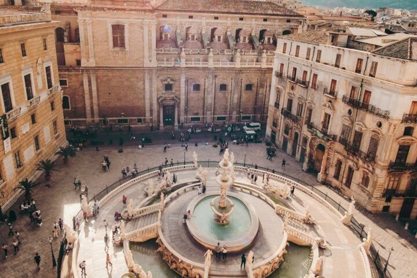 A historic square with a central fountain, surrounded by classical architecture. 1
