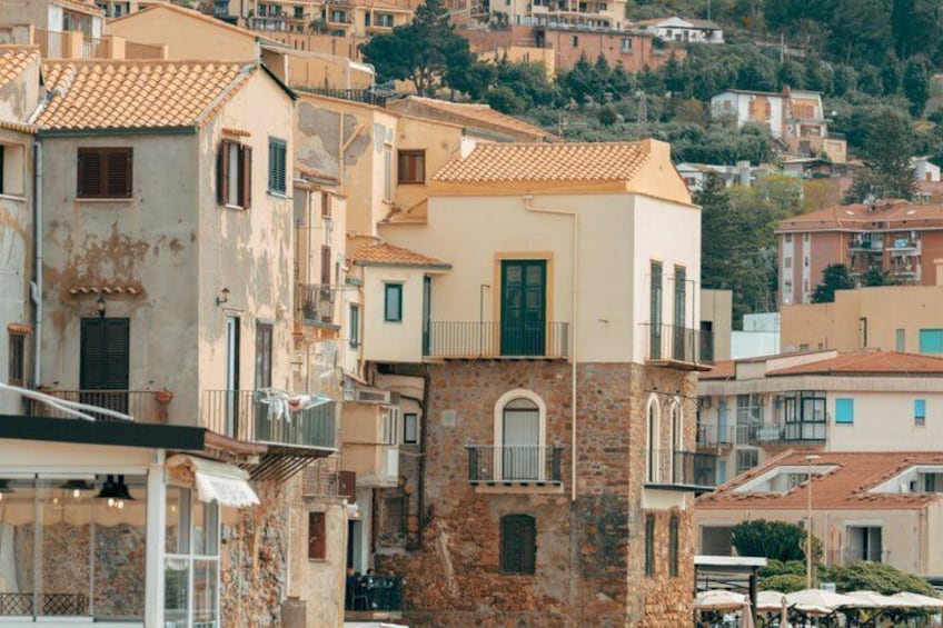 A hillside of terracotta-roofed buildings with balconies and a mix of stone and plaster facades. 4