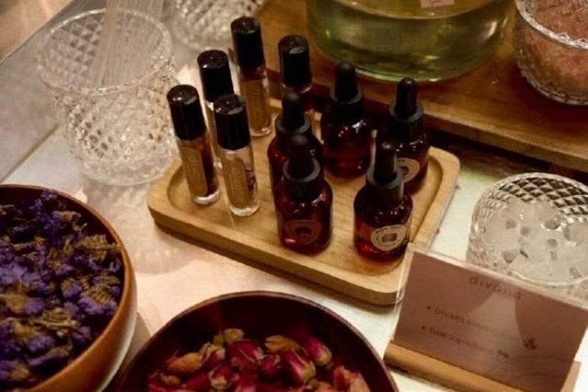 Una bandeja de madera con varias botellas pequeñas, presumiblemente con aceites esenciales, y dos cuencos con flores secas. 3