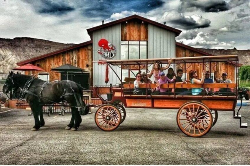 A horse-drawn carriage with passengers, a wooden building with a logo, and a mountainous backdrop. 1