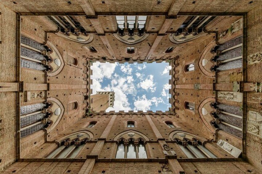 A symmetrical architectural structure with a central courtyard and a clear sky above. 3