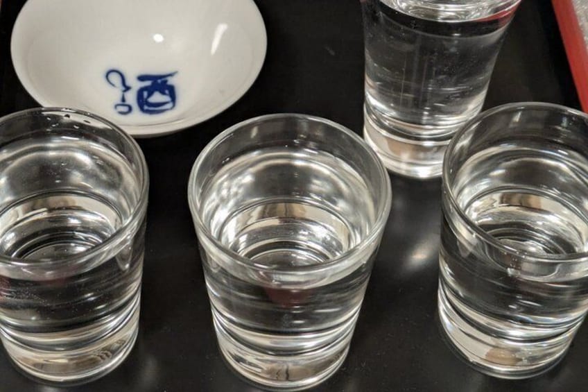 Four clear glasses of water and a white plate with blue text. 3