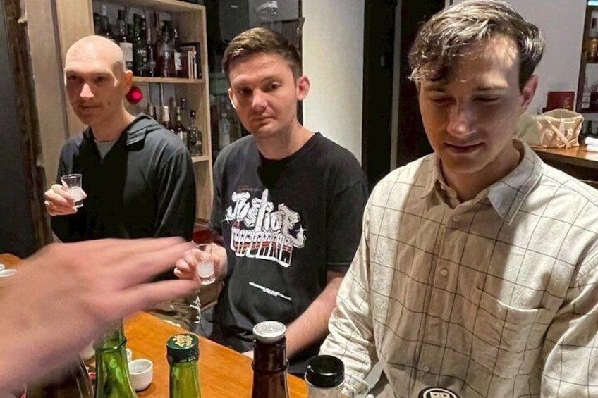 A group of people at a bar with bottles and glasses. 2