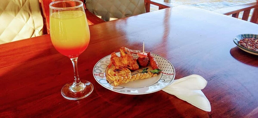A wooden table with a plate of grilled food and a glass of red beverage. 5