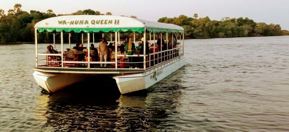A boat named 'WA-NUKA QUEEN' on calm water with passengers and a green canopy. 4
