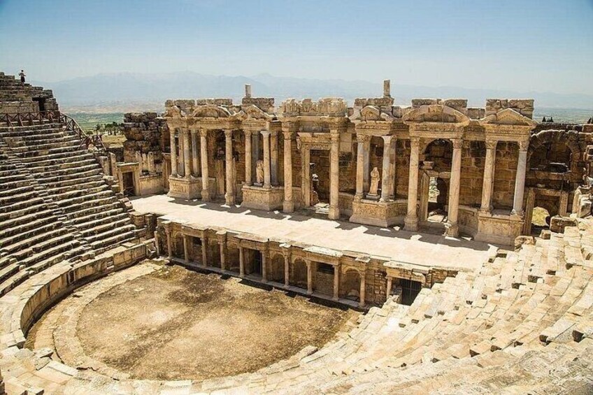 An ancient amphitheater with stone seating and columns. 5