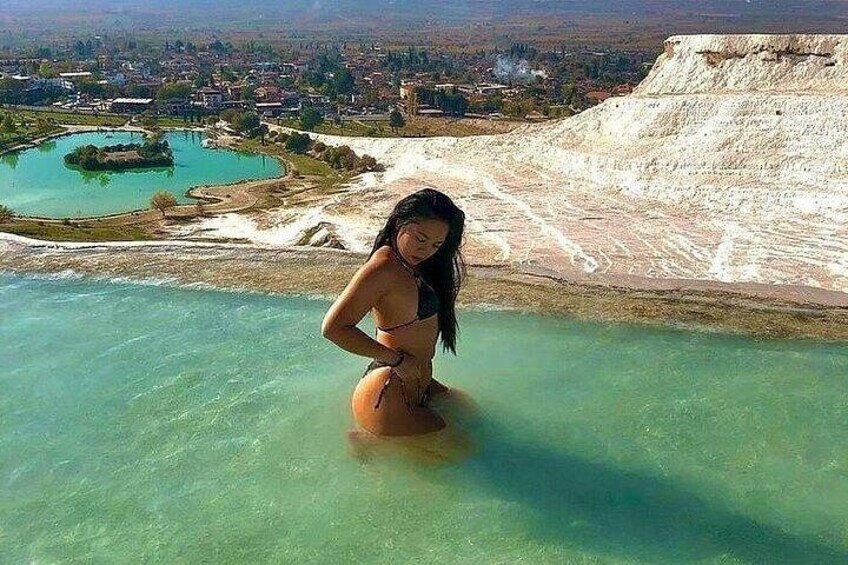 A person in a bikini near a turquoise pool with a white cliff and a small island in the background. 5