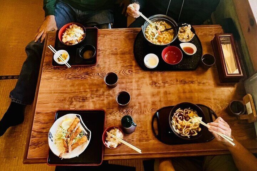 A wooden table with various dishes, chopsticks, and small bowls of sauce. 4