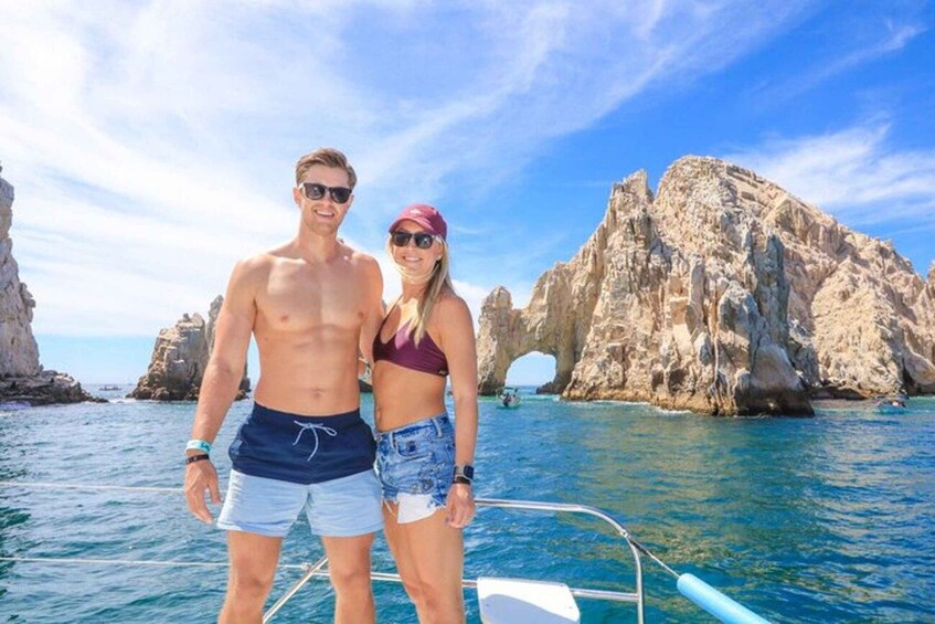 A couple on a boat with rocky cliffs and clear blue water in the background. 1
