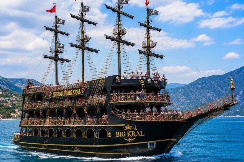 A large, ornate ship named 'BIG KRAI' with multiple decks and passengers, sailing on a body of water with mountains in the background. 4