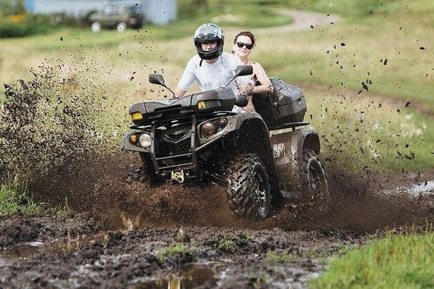 A quad bike in a muddy field with a person riding it. 2
