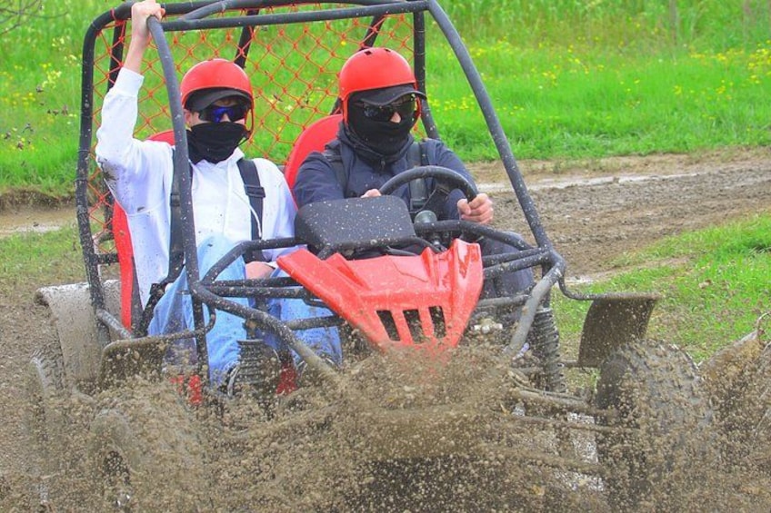 Two people in a red ATV on a muddy path. 2