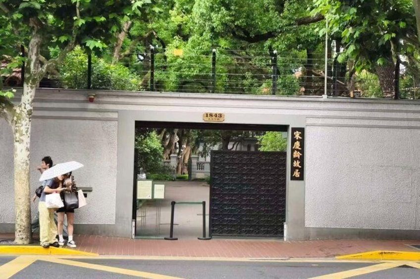 A building entrance with a sign, a tree, and a person holding an umbrella. 3