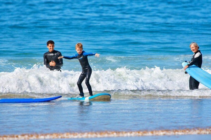 Three people surfing on a beach with waves. 5