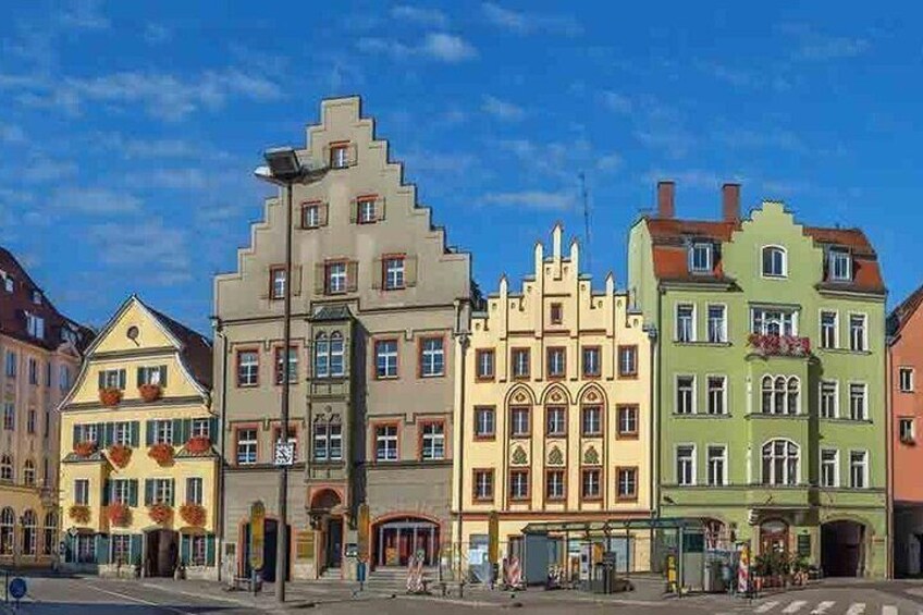 A row of colorful historic buildings with distinct architectural styles, a clear blue sky, and a pedestrian crossing. 2