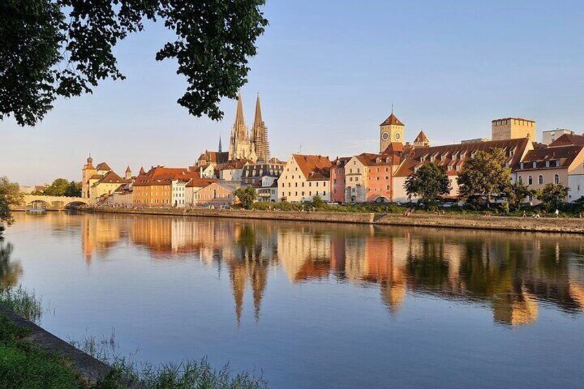 A calm river reflecting historic buildings, including a prominent church with twin spires. 3