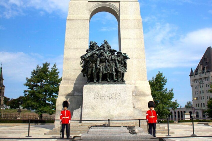A monument with a relief sculpture, two guards in red uniforms, and a date inscribed. 3
