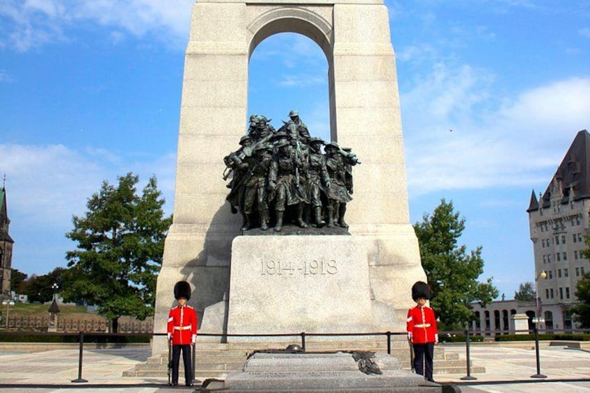 A monument with a relief sculpture and two guards in red uniforms. 2