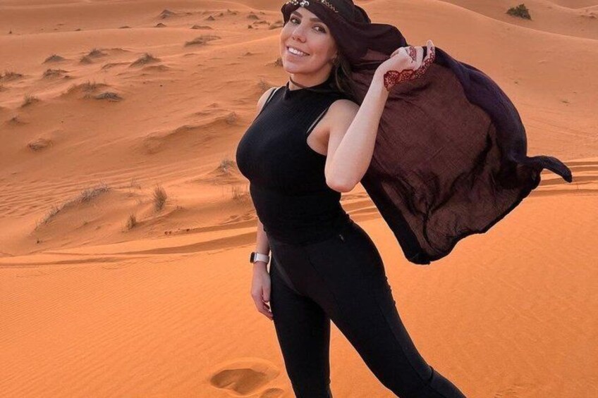 Una persona vestida de negro de pie sobre una duna de arena, con un paisaje desértico al fondo. 3