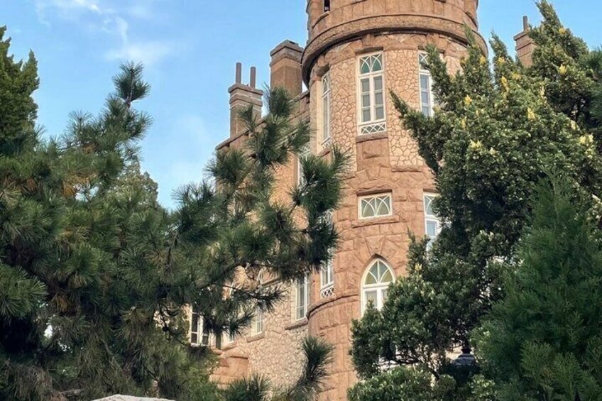 A stone tower with arched windows and a turret, surrounded by pine trees. 4