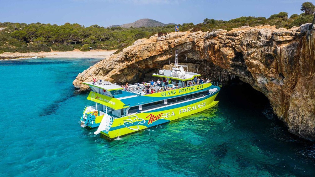 A glass bottom boat named 'New Sea Paradise' navigating through a rocky arch in clear turquoise waters. 5