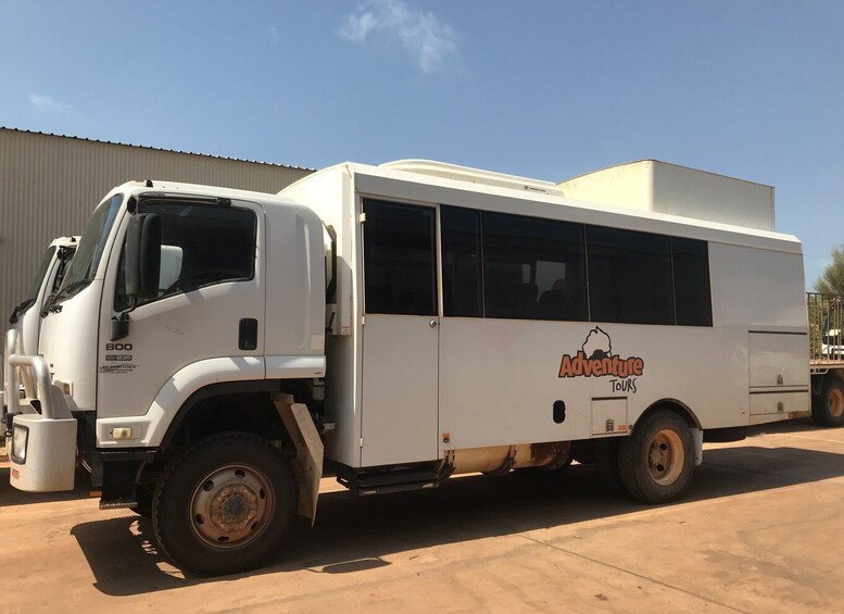 A white tour bus with 'Adventure Tours' branding parked in a lot. 3