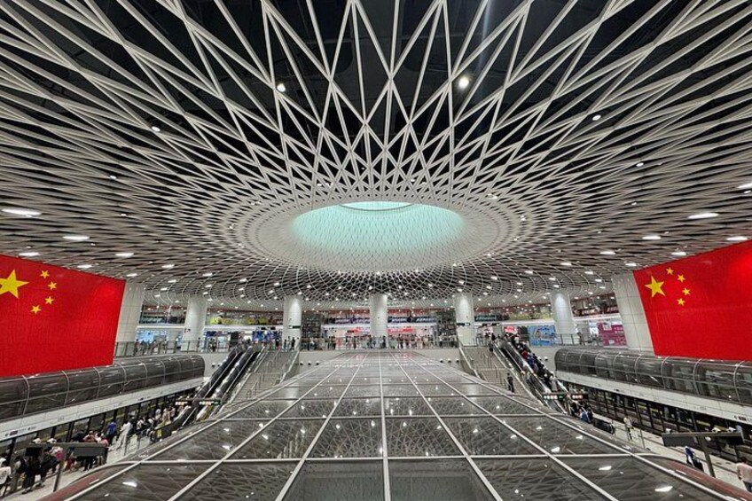 A spacious indoor area with a modern geometric ceiling design, large open spaces, and prominent Chinese flags. 3