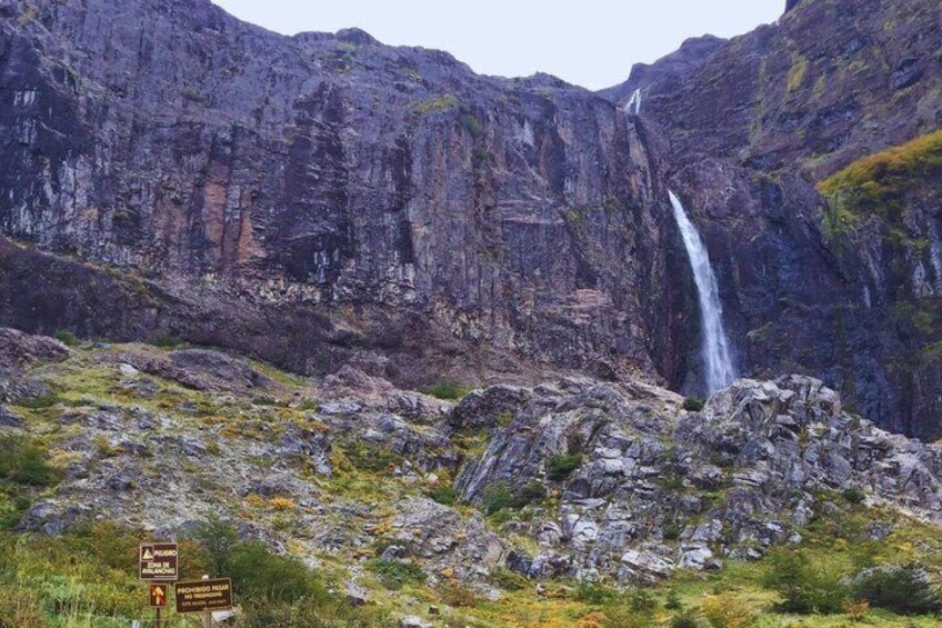 A waterfall cascading down a rocky cliff, surrounded by rugged terrain and sparse vegetation. 2