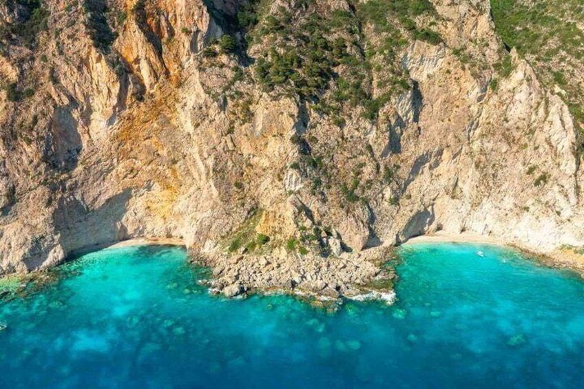 A rugged coastline with a natural rock formation and clear turquoise waters. 4