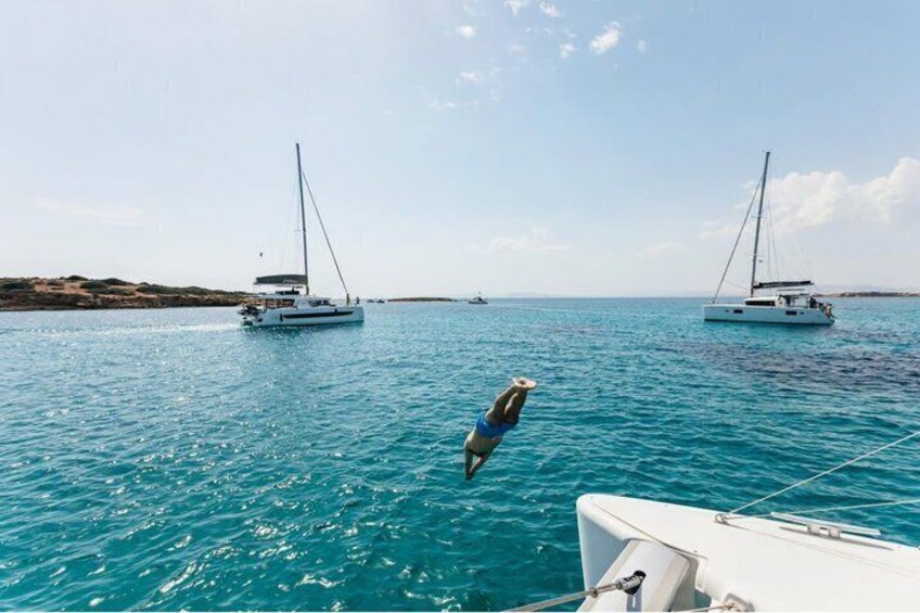 A person diving into the sea from a boat, with two sailboats in the background. 5