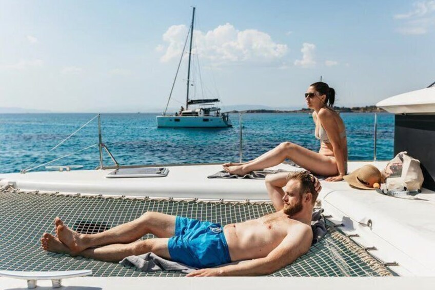 A man sunbathing on a boat with a woman sitting nearby. 3