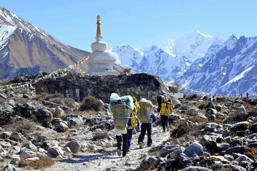 A group of hikers on a rocky mountain trail with a white stupa in the background. 5