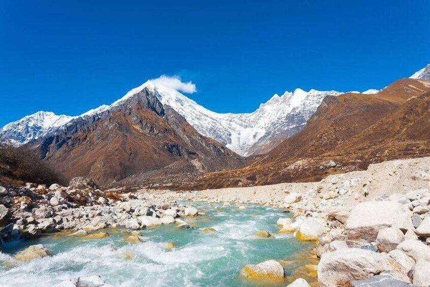 A river flowing through a rocky terrain with snow-capped mountains in the background. 3