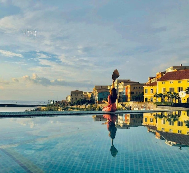 A person sitting by a pool with a view of colorful buildings and a calm sea. 4