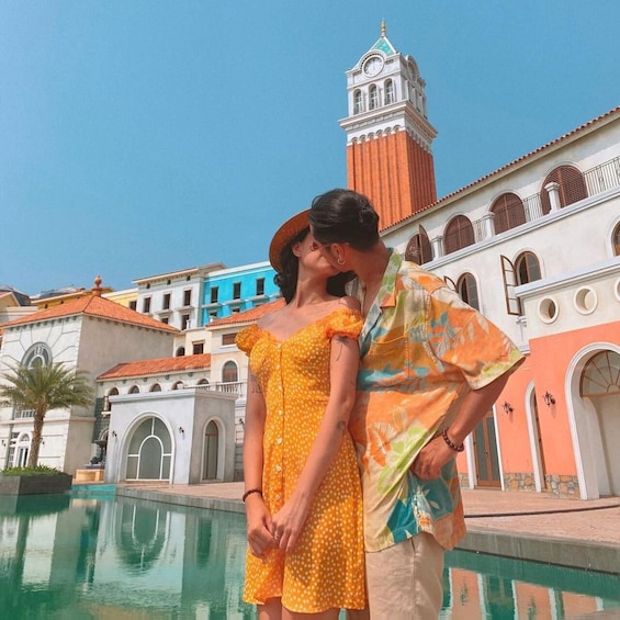 A couple by a pool with a historic building and a clock tower in the background. 5