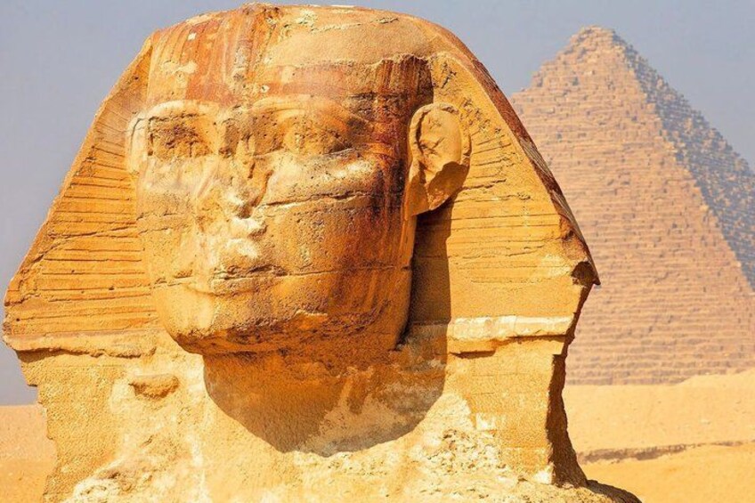 A large stone head with a pyramid in the background. 5