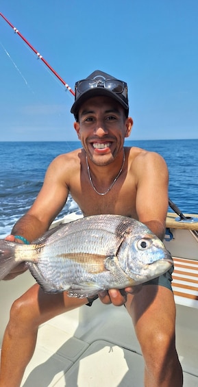 A person holding a fish on a boat with the ocean in the background. 1