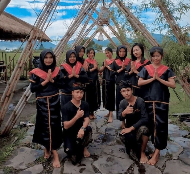 A group of people in traditional attire standing in front of a bamboo structure. 2
