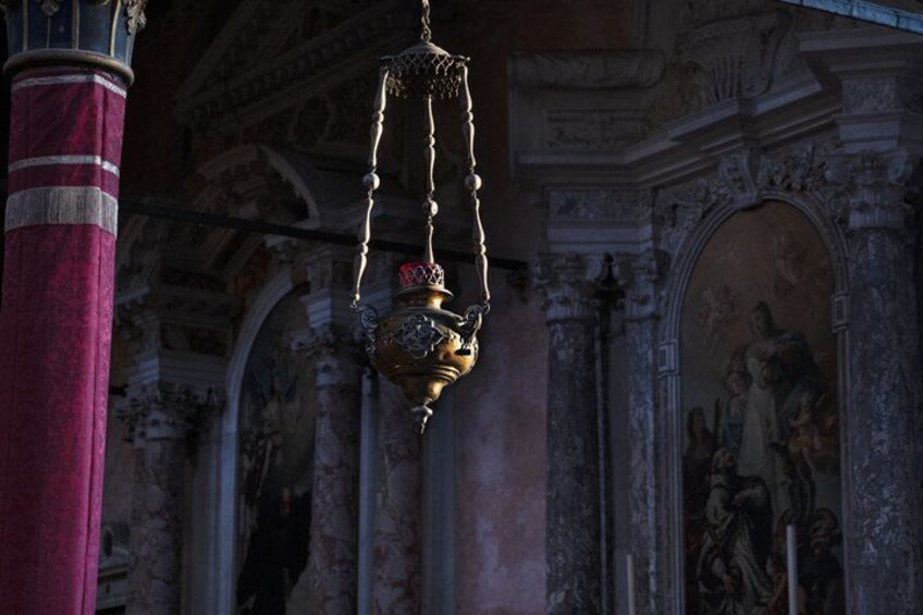 An ornate chandelier in a historic building with intricate wall paintings and architectural details. 5