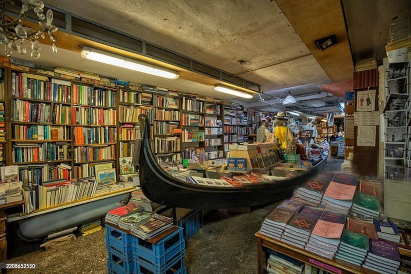 A bookstore with a gondola, bookshelves, and a few customers browsing. 3
